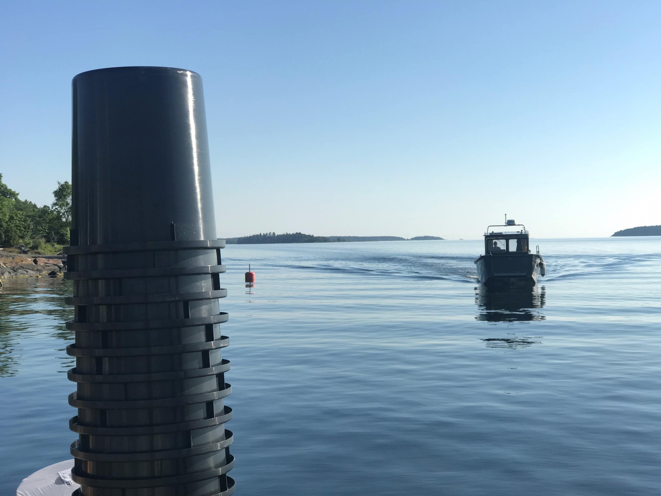 Tomma staplade latrintunnor i förgrunden och en båt i bakgrunden.